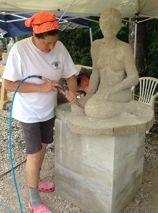 Amy Brier uses an air chisel to sculpt a figure out of Indiana limestone.